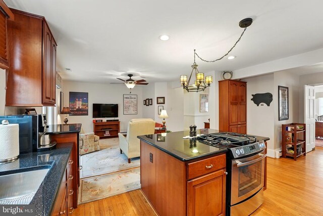 kitchen featuring stainless steel gas range, light wood-style floors, a ceiling fan, recessed lighting, and a center island