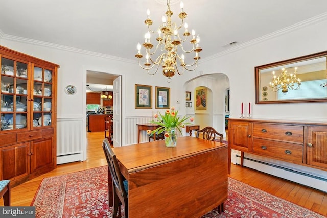 dining space featuring a baseboard heating unit, arched walkways, a chandelier, a baseboard radiator, and light wood finished floors