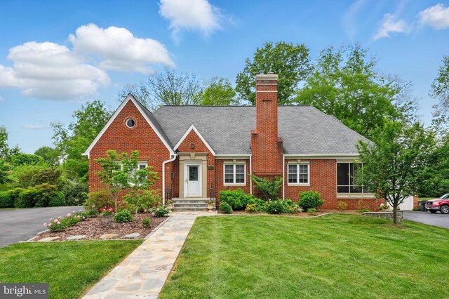 view of front of home with a front lawn, brick siding, and a chimney