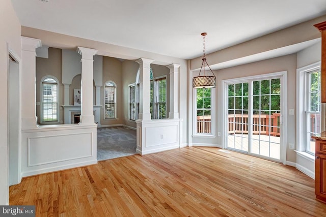 11211 Spring Meadow Blvd, Fredericksburg, VA 22407 - unfurnished dining area featuring decorative columns, light wood-type flooring, a decorative wall, and wainscoting