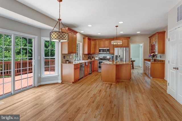 11211 Spring Meadow Blvd, Fredericksburg, VA 22407 - kitchen with appliances with stainless steel finishes, brown cabinets, light wood finished floors, light stone countertops, and tasteful backsplash