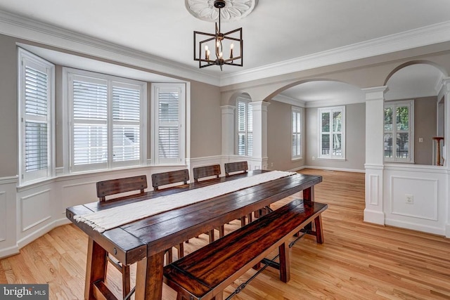 11211 Spring Meadow Blvd, Fredericksburg, VA 22407 - dining room featuring arched walkways, ornate columns, light wood-type flooring, a decorative wall, and a chandelier