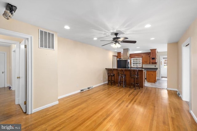 148 Red Hill Rd, Orange, VA 22960 - kitchen with black refrigerator, a peninsula, ventilation hood, brown cabinetry, and a kitchen bar