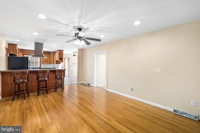 148 Red Hill Rd, Orange, VA 22960 - kitchen featuring black refrigerator, island range hood, brown cabinetry, a kitchen bar, and light wood-style flooring