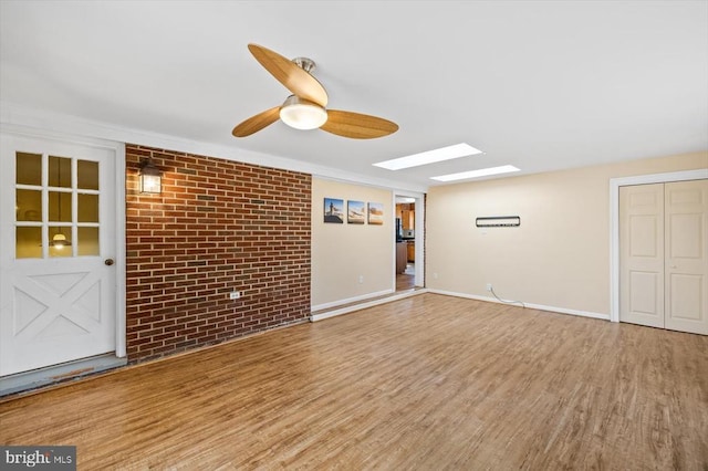 148 Red Hill Rd, Orange, VA 22960 - unfurnished living room with a skylight, wood finished floors, brick wall, a ceiling fan, and baseboards
