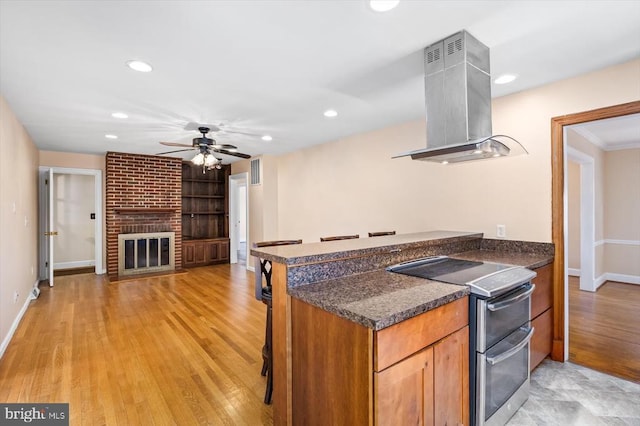 148 Red Hill Rd, Orange, VA 22960 - kitchen featuring island exhaust hood, range with two ovens, ceiling fan, baseboards, and a brick fireplace