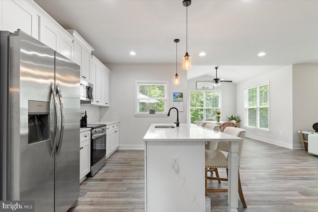 5509 Bazzanella Dr, Mineral, VA 23117 - kitchen with appliances with stainless steel finishes, a kitchen breakfast bar, light wood finished floors, a kitchen island with sink, and a ceiling fan