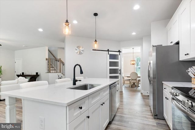 5509 Bazzanella Dr, Mineral, VA 23117 - kitchen featuring a barn door, stainless steel appliances, light wood-type flooring, recessed lighting, and white cabinets