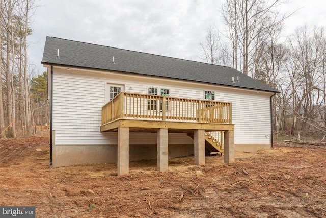 back of property featuring roof with shingles, stairway, and a wooden deck