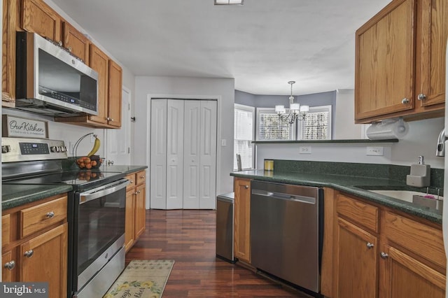 8802 Dundee Dr, Fredericksburg, VA 22408 - kitchen featuring appliances with stainless steel finishes, a chandelier, dark countertops, and brown cabinets