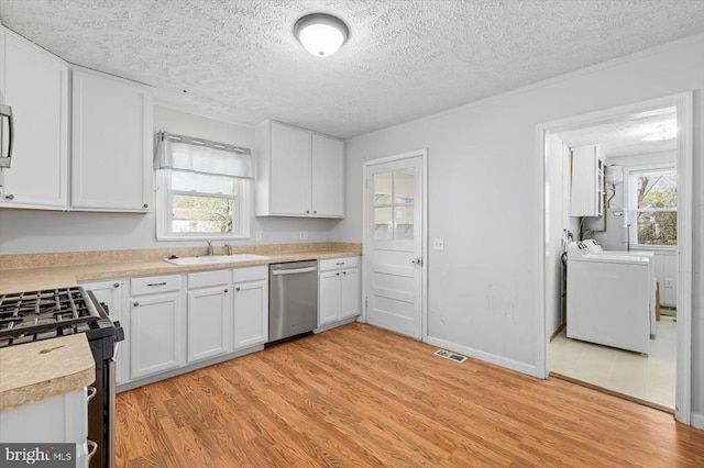 kitchen featuring dishwasher, a sink, light wood-type flooring, independent washer and dryer, and light countertops