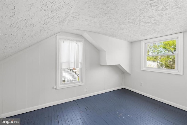 bonus room featuring a textured ceiling, baseboards, dark wood-type flooring, plenty of natural light, and lofted ceiling