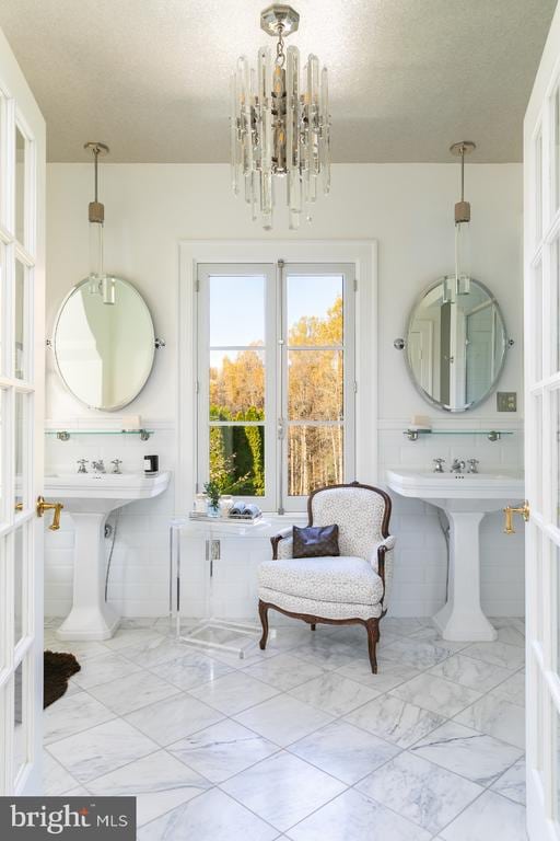  - bathroom featuring marble look tiles, a chandelier, and a textured ceiling