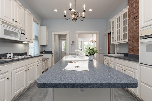 557 Wayne Ave S, Waynesboro, VA 22980 - kitchen with white appliances, a chandelier, a sink, dark countertops, and a center island