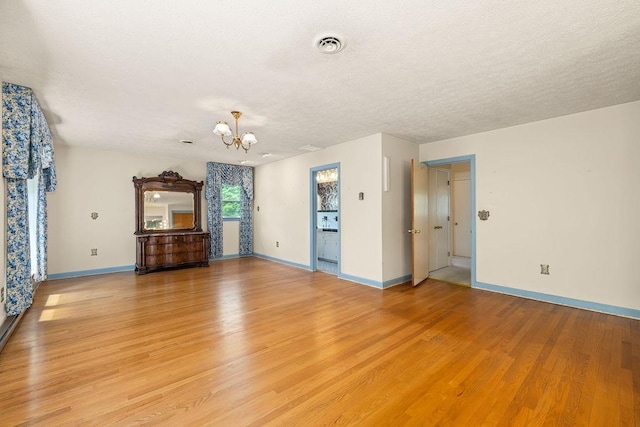 188 Middlebrook Rd, Staunton, VA 24401 - unfurnished living room with a chandelier, light wood finished floors, baseboards, and a textured ceiling