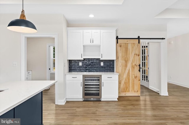 kitchen with beverage cooler, light wood-style flooring, white cabinets, decorative backsplash, and recessed lighting