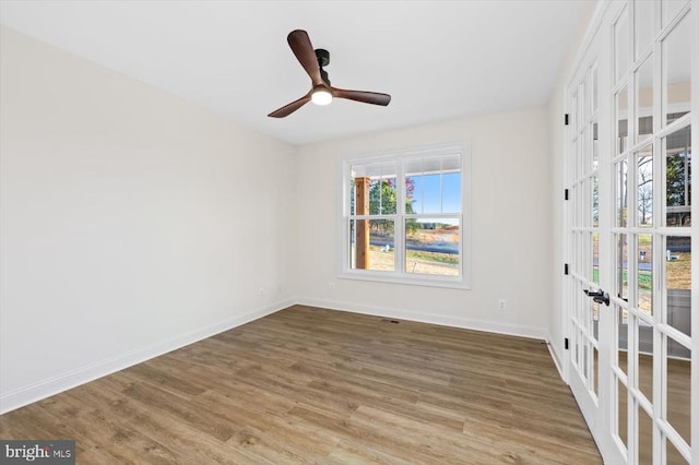 unfurnished room featuring french doors, baseboards, wood finished floors, and ceiling fan