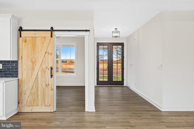 doorway with baseboards, wood finished floors, a barn door, french doors, and a chandelier