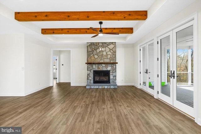 unfurnished living room with wood finished floors, french doors, ceiling fan, beam ceiling, and baseboards