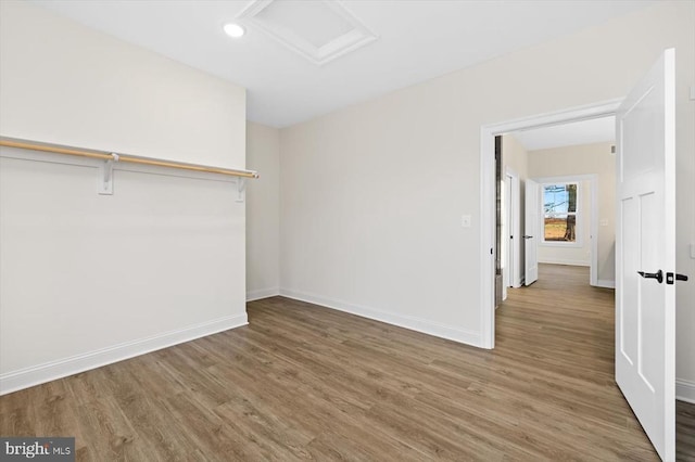 unfurnished bedroom with attic access, wood finished floors, baseboards, and recessed lighting