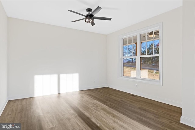 empty room featuring dark wood-style floors, baseboards, and ceiling fan