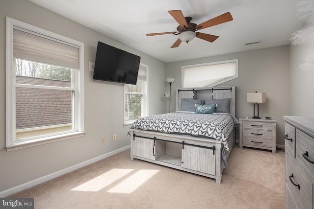 bedroom with light carpet, multiple windows, baseboards, and ceiling fan