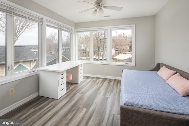 bedroom featuring light wood-style flooring, baseboards, an office area, and a ceiling fan
