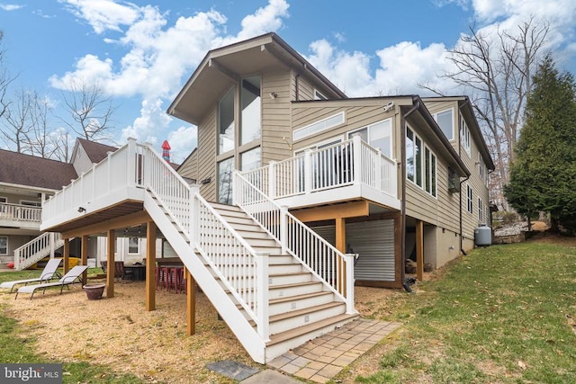 rear view of house with stairway, a lawn, and a wooden deck