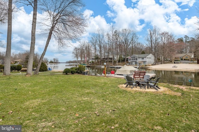 view of green lawn with a water view and an outdoor fire pit