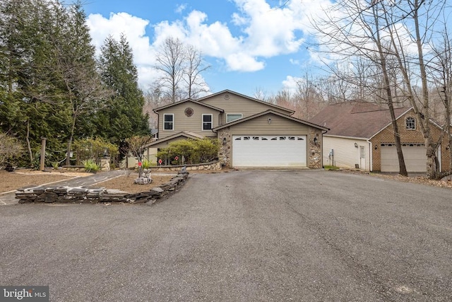 view of front of house with asphalt driveway, an attached garage, and stone siding