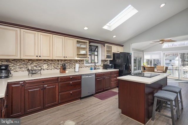 kitchen with black appliances, lofted ceiling, backsplash, plenty of natural light, and a skylight