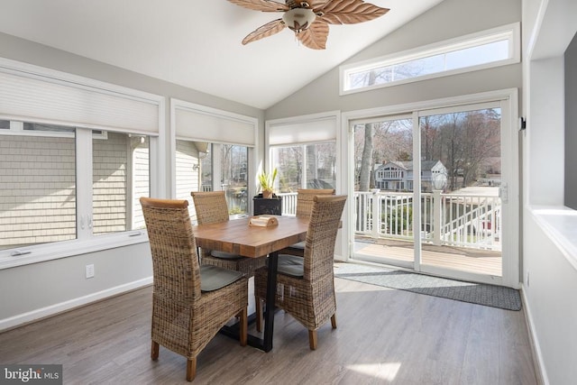 sunroom with wood finished floors, high vaulted ceiling, and baseboards