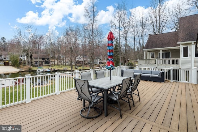 wooden terrace with a water view, outdoor dining area, a lawn, and outdoor lounge area