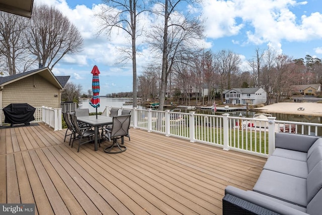 wooden deck with outdoor dining area, a water view, a yard, and grilling area