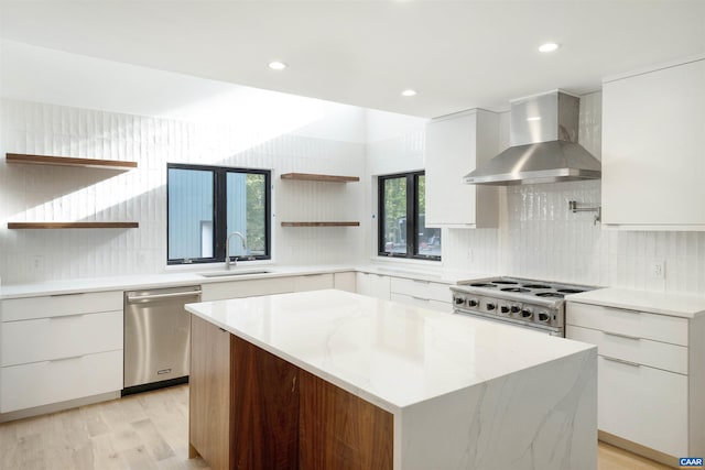 kitchen with stainless steel dishwasher, modern cabinets, a sink, open shelves, and wall chimney range hood