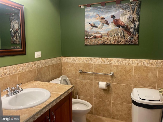  - bathroom with tile walls, toilet, vanity, and wainscoting