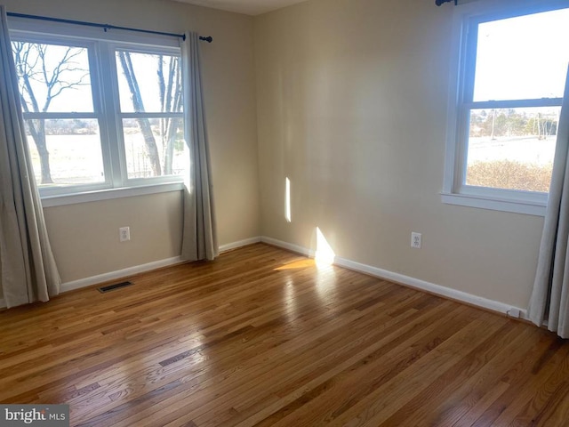  - unfurnished room featuring wood finished floors, healthy amount of natural light, and baseboards
