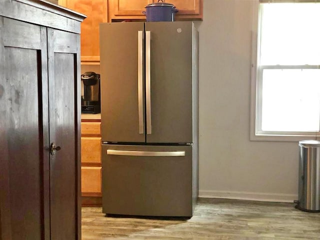 kitchen featuring freestanding refrigerator, light wood-type flooring, baseboards, and brown cabinets