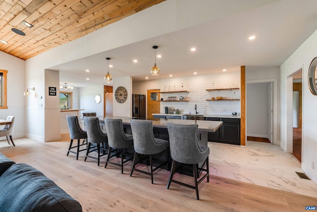 1900 Lowesville Rd, Amherst, VA 24521 - kitchen with a spacious island, black refrigerator with ice dispenser, a breakfast bar, backsplash, and open shelves