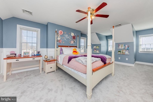 carpeted bedroom featuring wainscoting, visible vents, and multiple windows