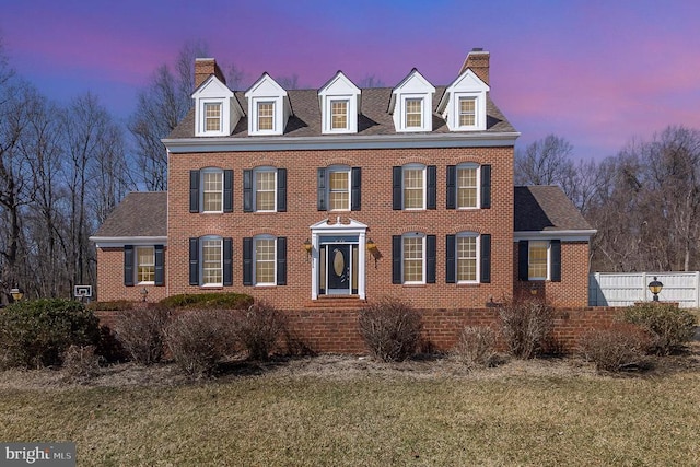 view of front of home featuring a chimney, roof with shingles, fence, a yard, and brick siding