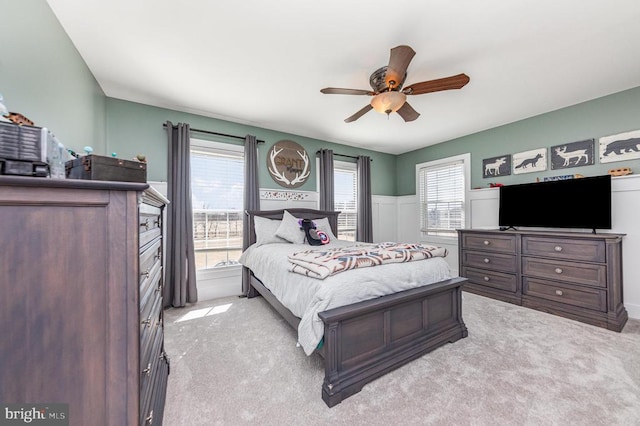 carpeted bedroom featuring a wainscoted wall and ceiling fan