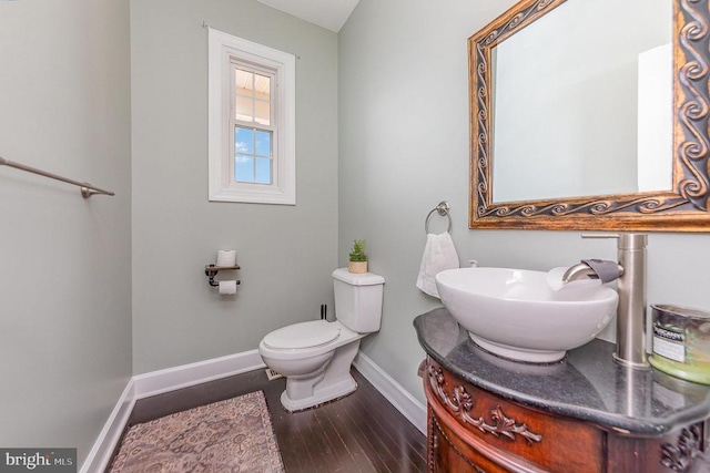 bathroom with toilet, vanity, baseboards, and wood finished floors