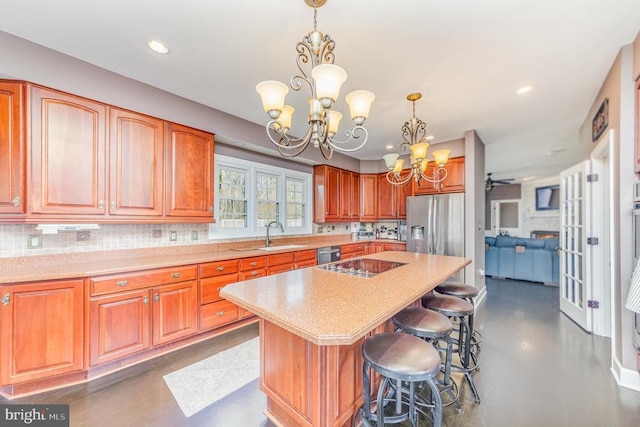 kitchen with light countertops, appliances with stainless steel finishes, a kitchen island, and tasteful backsplash