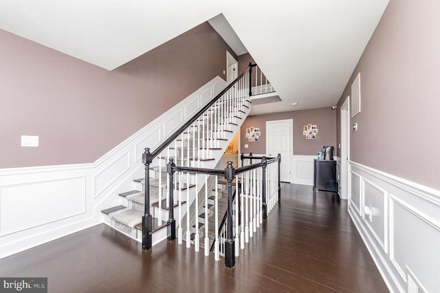 staircase with wainscoting, a decorative wall, and wood finished floors