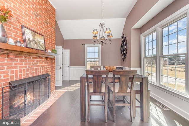 dining area featuring a brick fireplace, wood finished floors, and a healthy amount of sunlight