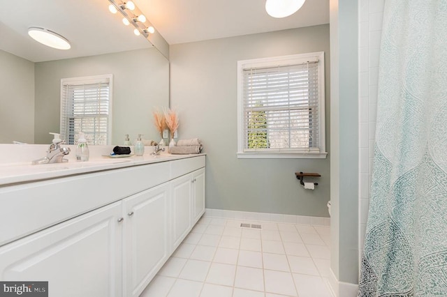 bathroom with double vanity, visible vents, a sink, tile patterned flooring, and baseboards