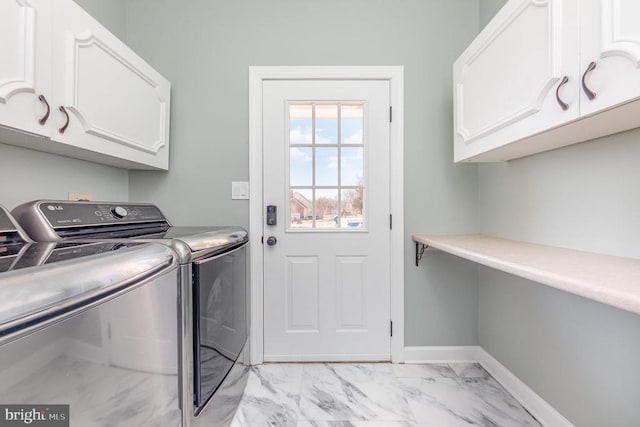 washroom featuring cabinet space, baseboards, marble finish floor, and washer and dryer