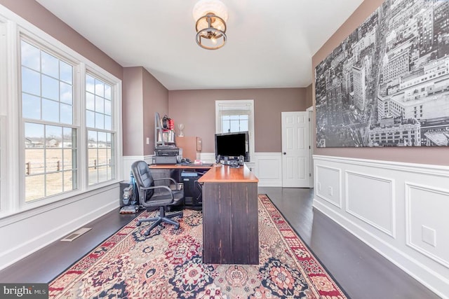 office with dark wood-style floors, wainscoting, and visible vents