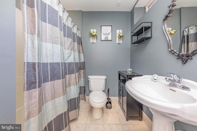 full bath featuring a shower with shower curtain, a sink, toilet, and tile patterned floors